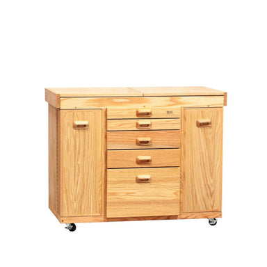 The BEST Shawn's Watercolor Station by BEST is a light wooden cabinet with a smooth varnished finish, featuring two vertical doors on each side and five centrally aligned supply drawers. It is mounted on small caster wheels, allowing for mobility.