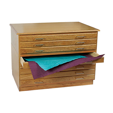 A BEST Best Oak Flat File with six drawers, four closed and two partially open, displaying large sheets of blue and purple artist paper. The cabinet has metal handles on each drawer.