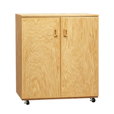 A wooden cabinet with a light oak finish and two doors. Each door has a rectangular handle near the top. The BEST Art Cart is mounted on four small black wheels, allowing for easy movement. The wood has a visible grain pattern, making it the BEST Art Cart for any creative space.